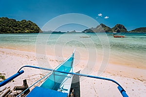 Traditional banca boat at Las cabanas beach in front of blue lagoon and exotic nature scenery in El Nido, Palawan