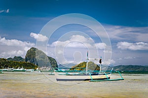 Traditional banca fishermen boat in shallow lagoon on Corong Beach. Nido, Philippines. Blue sky and clouds over Bacuit
