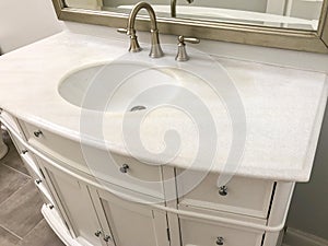 Traditional bathroom with white cabinets and marble countertop, two sinks and faucets with stone floor