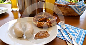 traditional Bavarian meal: white sausages, salty pretzels, sweet mustard, German beer and basket of prezels on Bavarian napkin