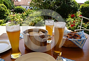 traditional Bavarian meal: white sausages, salty pretzels, sweet mustard, German beer and basket of prezels on Bavarian napkin