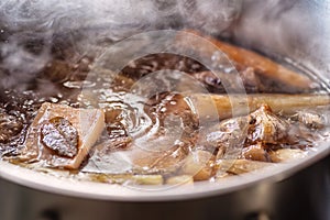 Traditional beef broth with vegetable, bones and ingredients in pot, cooking recipe photo