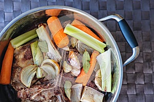 Traditional beef broth with vegetable, bones and ingredients in pot, cooking recipe