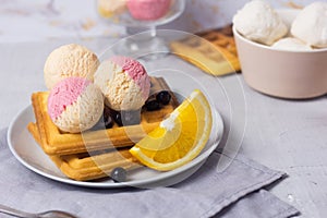 Traditional Belgian waffles with fruit ice-cream on gray plate. Orange and blueberry taste