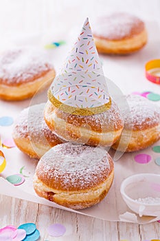 Traditional Berliner with party hat for carnival and party. German Krapfen or donuts with streamers and confetti