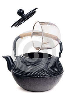 Traditional black Asian cast iron kettle teapot on wooden stand and clay cup on red background