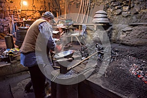 Traditional blacksmith manually forging the molten metal