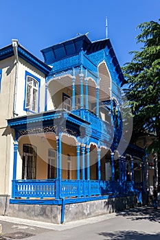 Traditional Borjomi building facade with blue carved wooden balcony and terrace in oriental style, Georgia