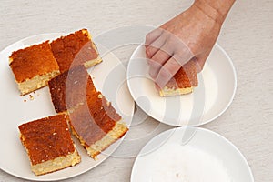 Traditional Brazilian dessert known as BOLO GELADO in Portuguese - Making step by step: Hand putting piece of cake in milk