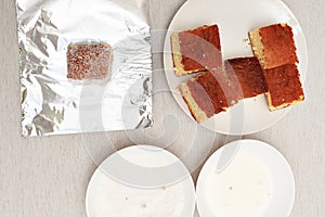 BOLO GELADO - Making step by step: Pieces of cake, aluminum foil, plates with milk and grated coconut photo
