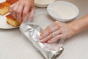 Traditional Brazilian dessert known as BOLO GELADO in Portuguese - Making step by step: Woman hand wrapping sliced cake photo