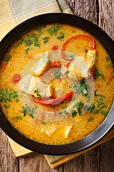 traditional Brazilian dish Moqueca Baiana of fish and bell peppers in a delicately coconut sauce close-up. Vertical top view