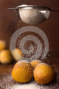 Traditional Brazilian mini fried cake called bolinho de chuva with falling sugar in wood background photo