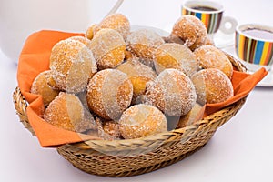Traditional Brazilian mini fried cakes called bolinho de chuva in a basket in white breakfast table background photo