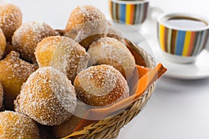 Traditional Brazilian mini fried cakes called bolinho de chuva in a basket in white breakfast table background close photo