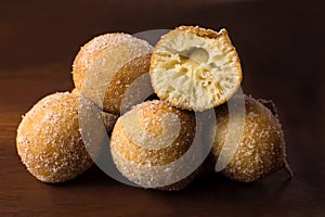 Traditional Brazilian mini fried cakes called bolinho de chuva with one open in wood background photo