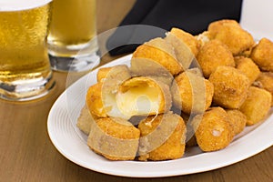 Traditional Brazilian pub food provolone cheese in breadcrumbs called provolone a milanesa with one open in a wood table close