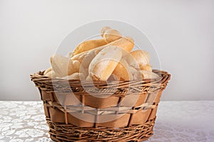 Traditional Brazilian starch biscuit called biscoito de polvilho in a basket on a table covered with white tablecloth, selective photo