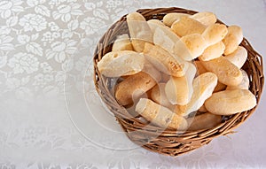 Traditional Brazilian starch biscuit called biscoito de polvilho in a basket on a table covered with white tablecloth, selective photo