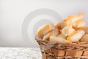 Traditional Brazilian starch biscuit called biscoito de polvilho in a basket on a table covered with white tablecloth, selective photo