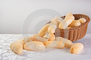 Traditional Brazilian starch biscuit called biscoito de polvilho in a basket on a table covered with white tablecloth, selective photo
