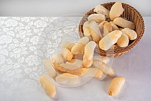 Traditional Brazilian starch biscuit called biscoito de polvilho in a basket on a table covered with white tablecloth, selective photo