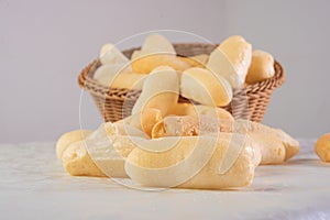 Traditional Brazilian starch biscuit called biscoito de polvilho in a basket on a table covered with white tablecloth, selective photo