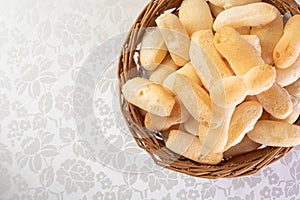 Traditional Brazilian starch biscuit called biscoito de polvilho in a basket on a table covered with white tablecloth, Top view photo