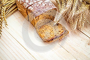 Traditional bread. Fresh loaf of rustic traditional bread with wheat grain ear or spike plant on wooden texture background. Rye
