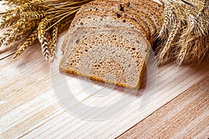 Traditional bread. Fresh loaf of rustic traditional bread with wheat grain ear or spike plant on wooden texture background. Rye