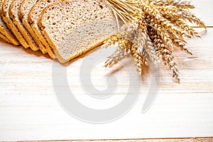 Traditional bread. Fresh loaf of rustic traditional bread with wheat grain ear or spike plant on wooden texture background. Rye