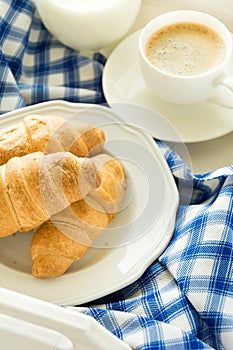Traditional breakfast with fresh croissants, milk and espresso on white wooden salver