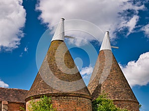 Traditional brick built oast houses with white chimneys in Kent, UK. Taken on a sunny day with blue sky in summer