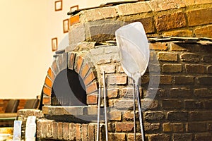 Traditional brick oven. Pizza paddle leaning against stone.