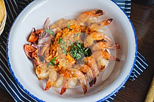 Traditional bright shrimp risotto in a bowl on a table in a restaurant with a beautiful decor in a dark key close-up.