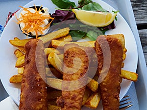 Traditional British fish and chips served with potato and lemon