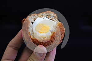 Traditional british food. Half eaten Scotch egg. Hard boiled-egg wrapped in sausage meat coated in bread crumbs and baked or deep photo