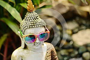 traditional buddha wearing colorful modern sunglasses, zen garden