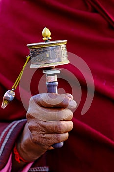 A traditional Buddhist prayer wheel in the hand of an old man in