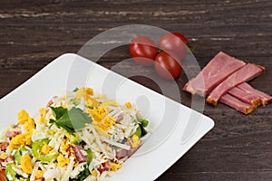 Traditional Bulgarian Shepherd salad with tomatoes, peppers, cucumbers, mushrooms, ham, cheese and eggs in white dish