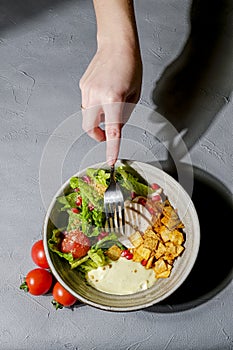 Traditional caesar salad in a white bowl on a dark gray table background. Selected focus
