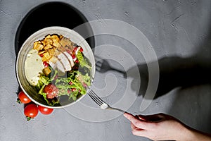 Traditional caesar salad in a white bowl on a dark gray table background. Selected focus