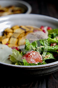 Traditional caesar salad in a white bowl on a old dark rustic table. Selected focus