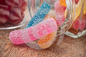 traditional candies falling from glass container on w