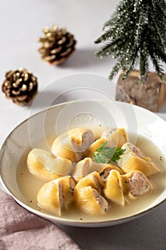 Traditional Catalan Christmas dish Escudella in white plate on table, stuffed pasta in meat broth, top view