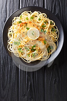 Traditional chicken Francaise with spaghetti with lemon sauce close-up on a plate. Vertical top view