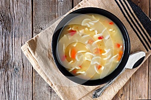 Traditional chicken noodle soup, above scene on rustic wood
