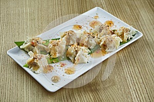 Traditional Chinese cuisine - Dim Sum with chicken, pork or seafood on a white ceramic plate with sweet and sour sauce on wooden