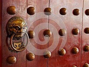 Traditional Chinese doors with brass handles symbolic of lion's heads