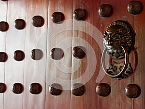 Traditional Chinese doors with brass handles symbolic of lion's heads